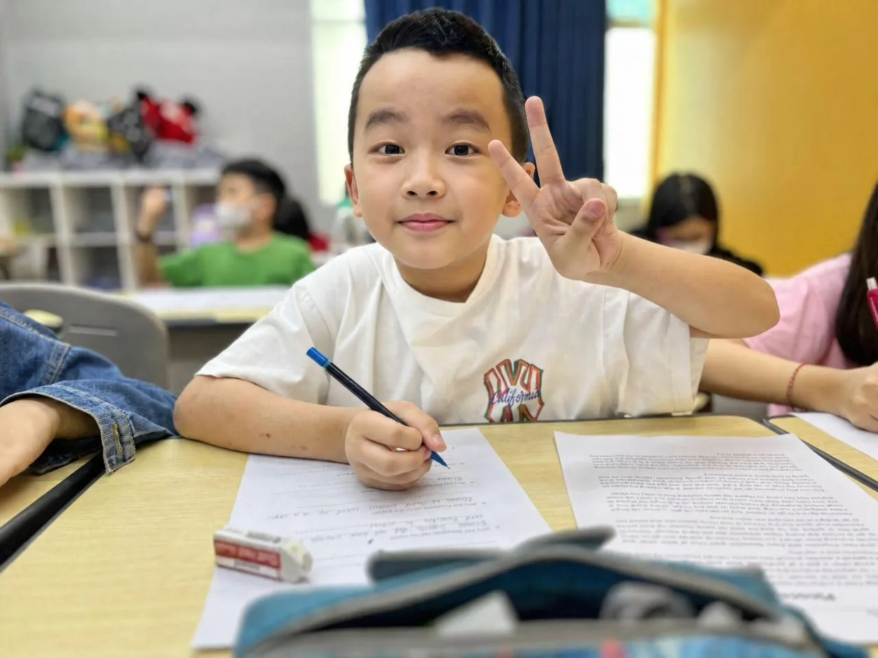 A TITAN student looking up from his written schoolwork, pen in hand
