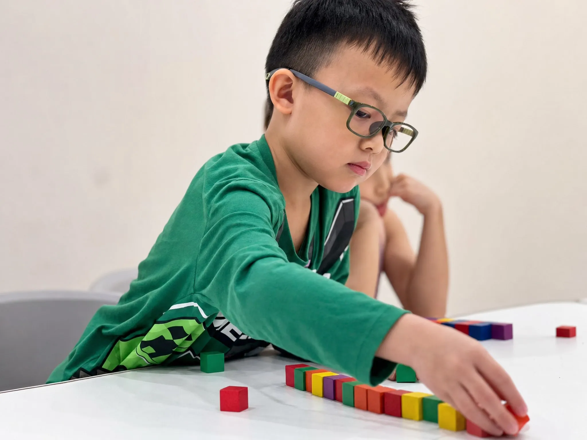 A TITAN student laying out coloured cubes in a sequence at his desk